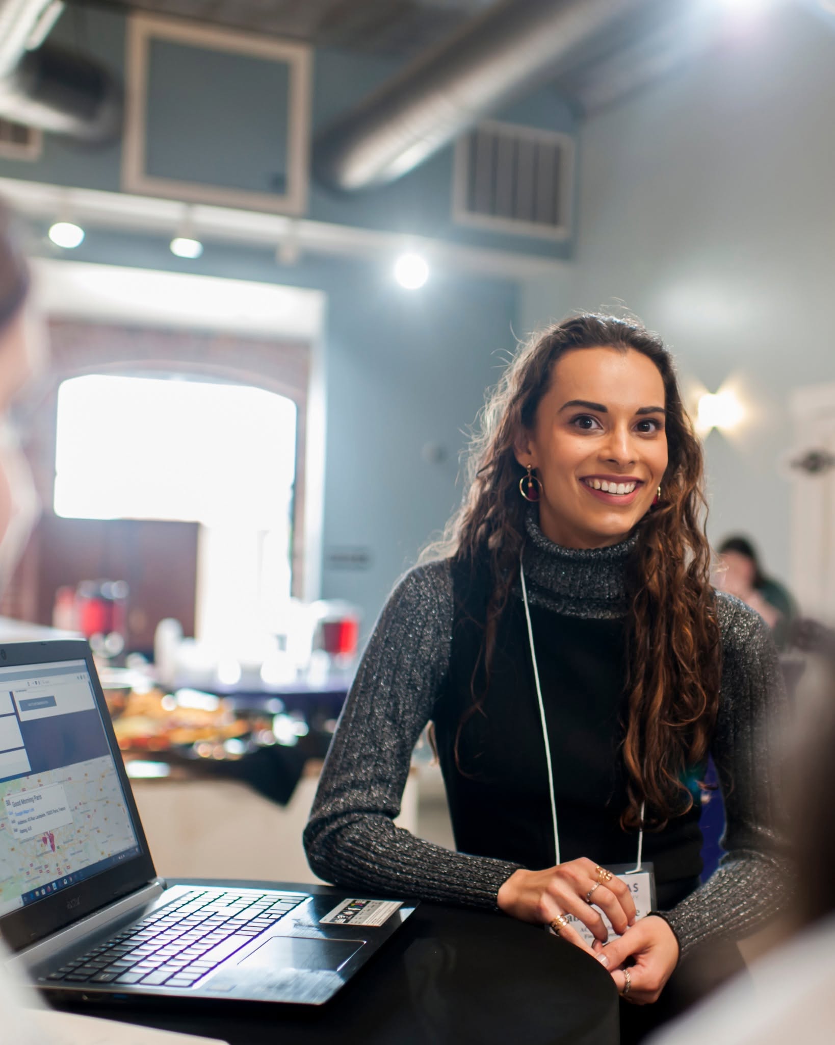 Female ArCA student smiling with laptop at an event